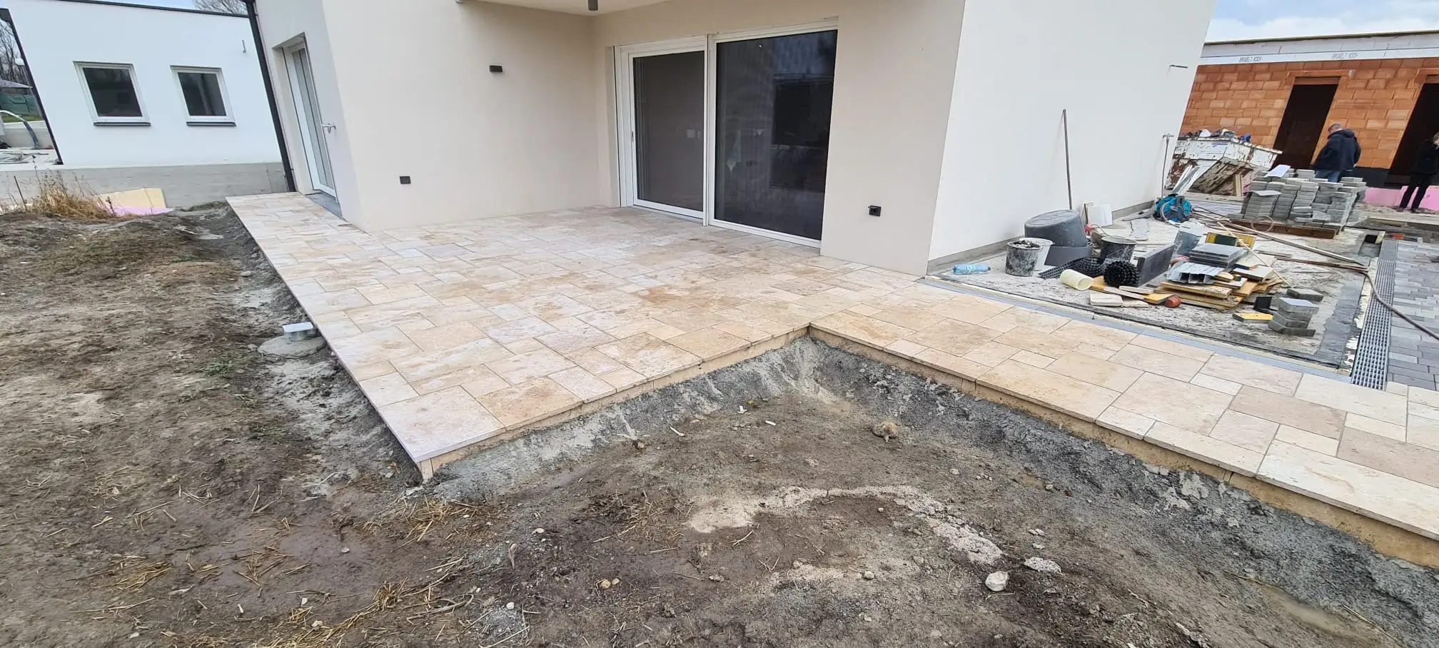 Bagger Wien – EMK Erdbau GmbH – Einfamilienhaus – Außenanlage – Gartengestaltung Bau einer Terrasse und eines Weges rund um ein Einfamilienhaus durch die EMK Erdbau GmbH.