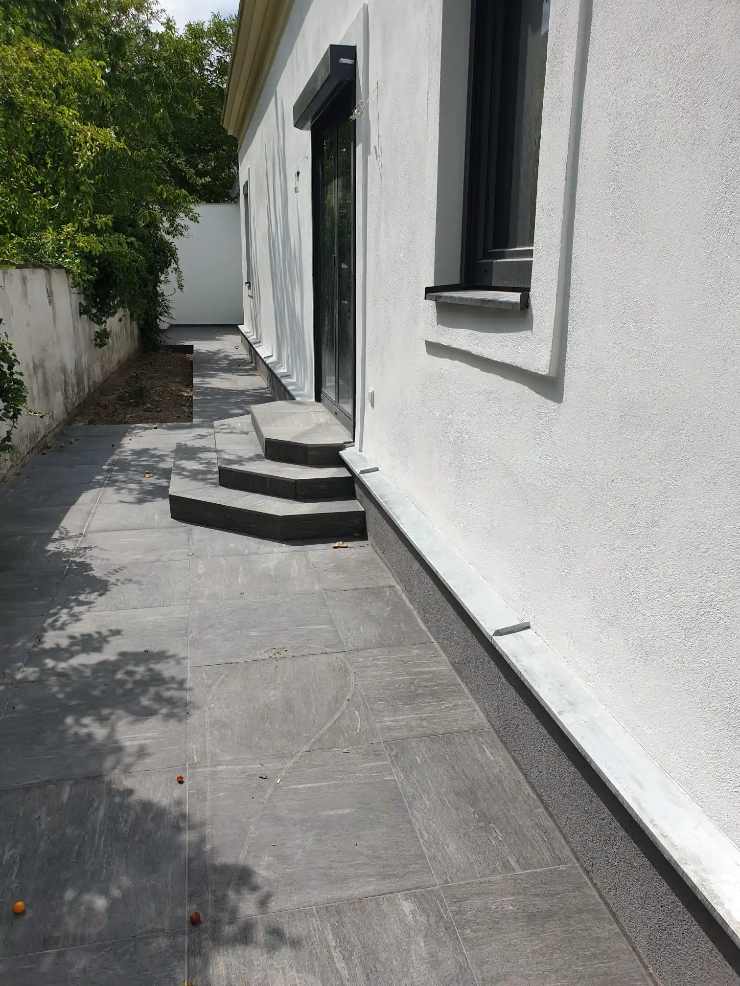 Bagger Wien – EMK Erdbau GmbH – Einfamilienhaus – Außenanlage – Wegbau Bau einer Terrasse und eines Weges rund um ein Einfamilienhaus durch die EMK Erdbau GmbH.