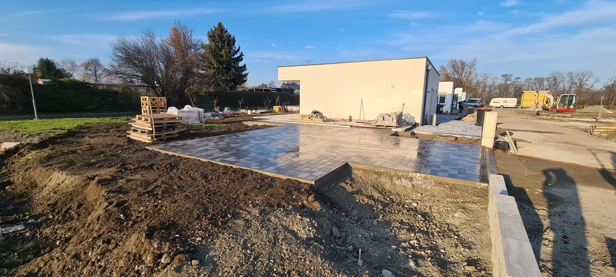 Bagger Wien – EMK Erdbau GmbH – Einfamilienhaus – Garage – Pflasterung Bau einer Einfahrt und eines Weges rund um ein Einfamilienhaus durch die EMK Erdbau GmbH.