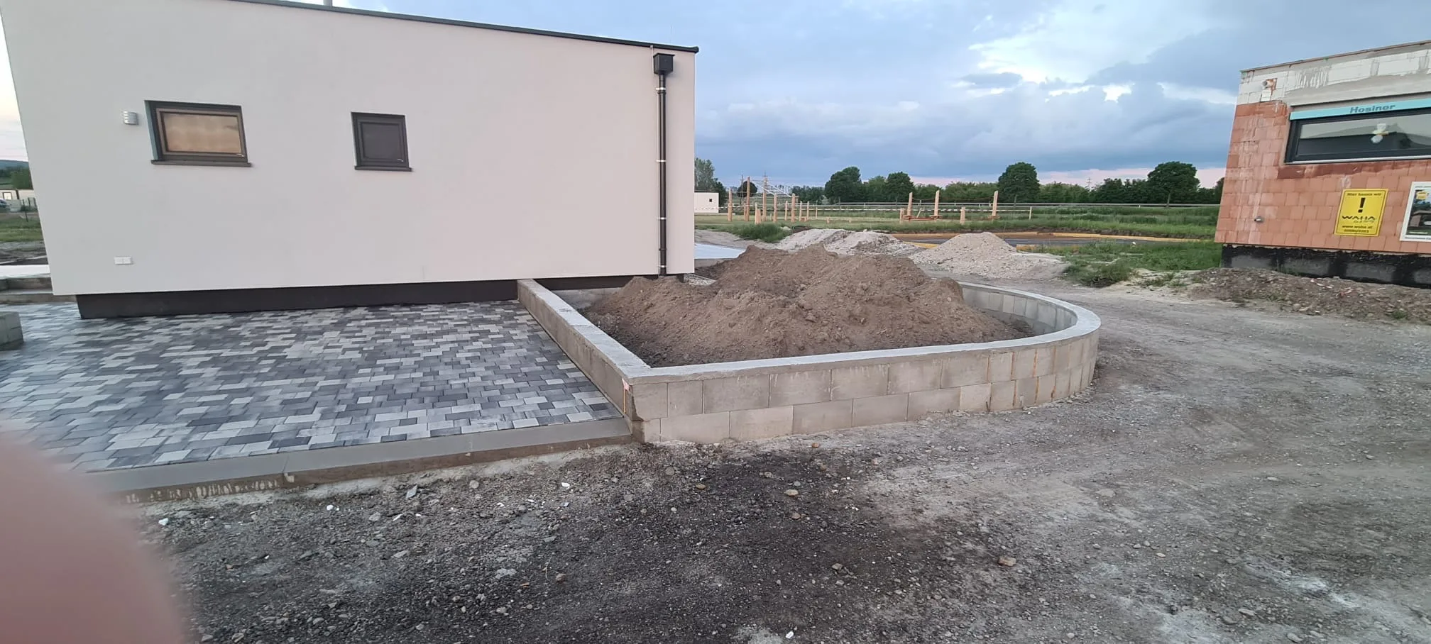 Bagger Wien – EMK Erdbau GmbH – Einfamilienhaus – Hausbau – Außenanlagen Bau einer Einfahrt und eines Weges rund um ein Einfamilienhaus durch die EMK Erdbau GmbH.