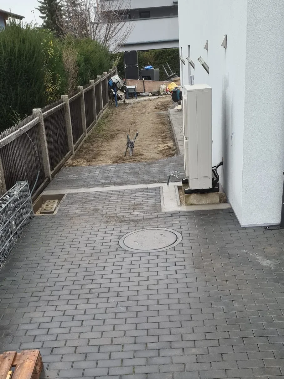 Bagger Wien – EMK Erdbau GmbH – Einfamilienhaus – Pflasterung – Gartengestaltung Bau einer Einfahrt und eines Weges rund um ein Einfamilienhaus durch die EMK Erdbau GmbH.